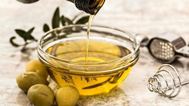 Olive oil being poured into a glass bowl. 