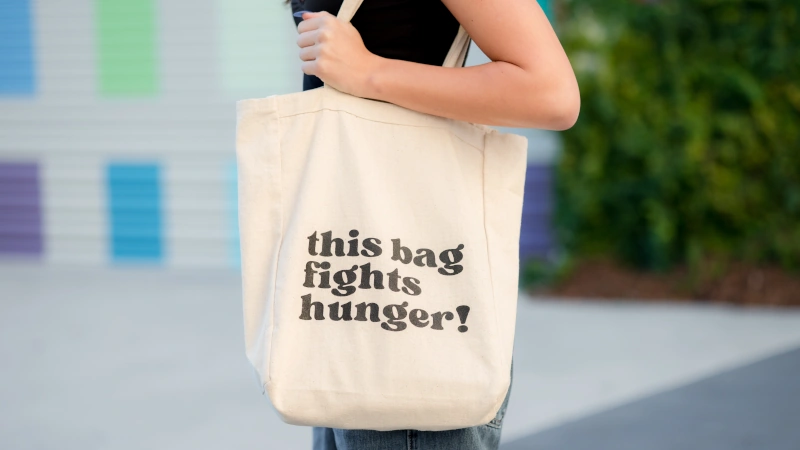 'this bag fights hunger' tote bag being carried.