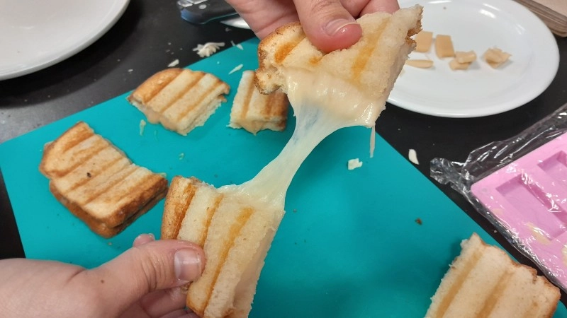 Person pulling apart a grilled cheese made with creamy plant-based gouda cheese.