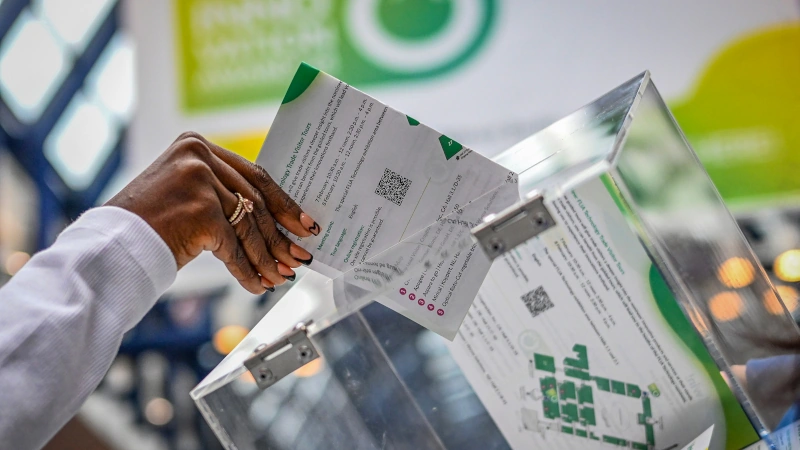 Person placing ballot in a clear box.