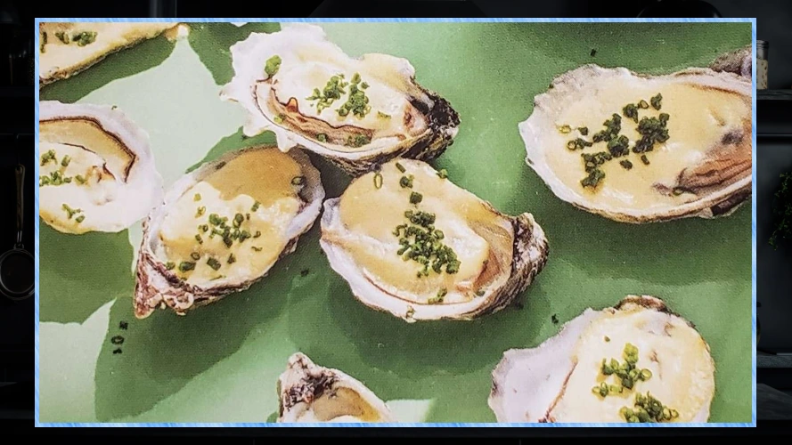 Roasted Oysters On A Half Shell with cream and chives on a green plate.