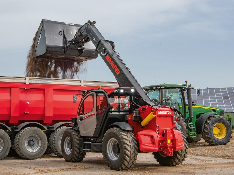 Manitou MLT 850 dumping dirt into a dump trailer.