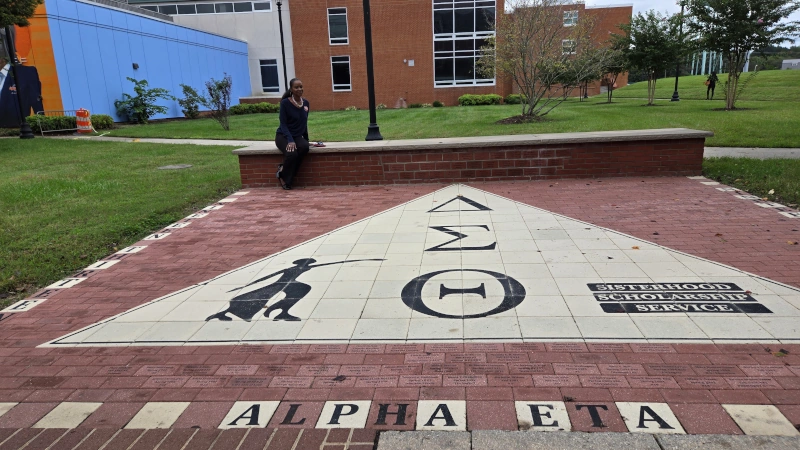 Gwen Williams-Dandridge sitting behind her sorority logo.