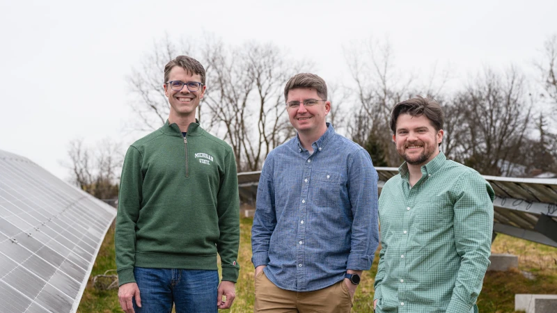 Three college students in a solar field.