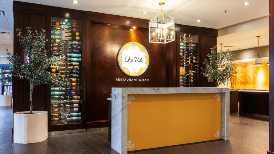 Main entrance to Che Vita with logo on brown wall and guest desk.