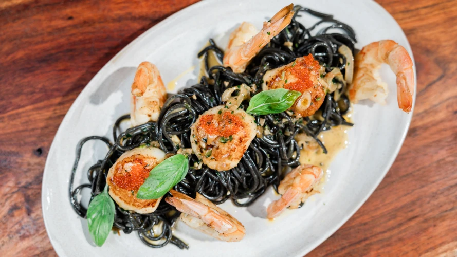Che Vita's Shrimp Scampi with ink squid pasta on a white plate.
