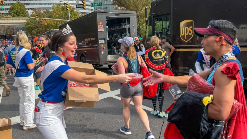 Woman hands watermelon to a runner.