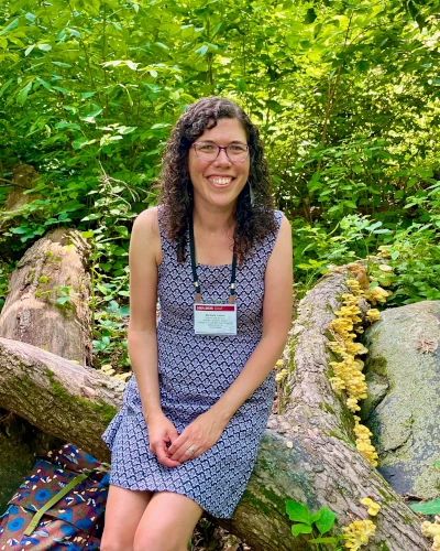 Woman sitting on a fallen tree in forest.