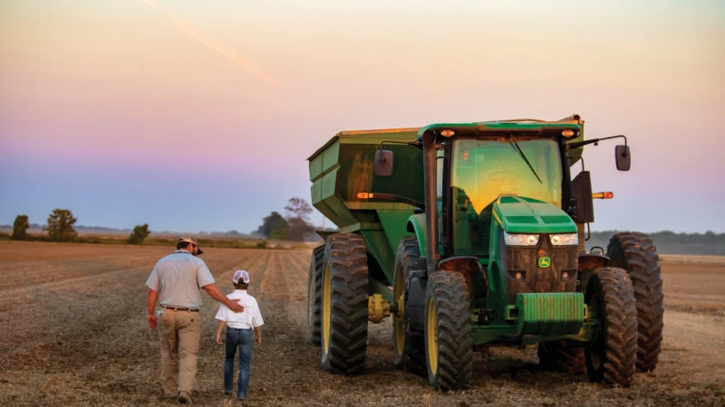 Farm farther and son next to a tractor.