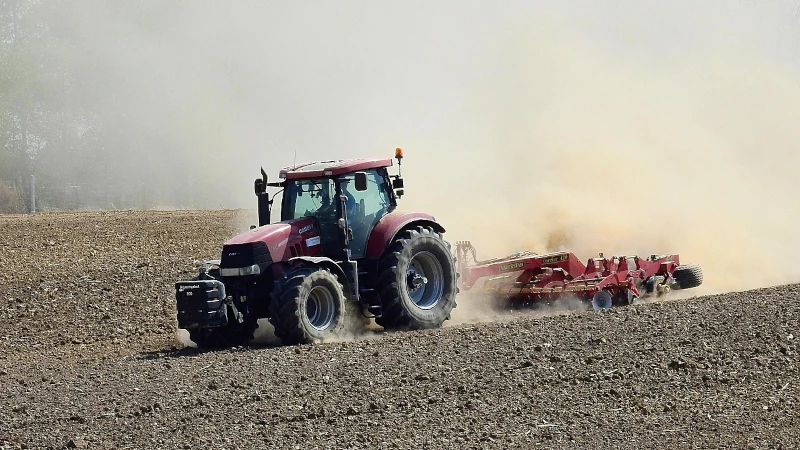 Tractor tilling soil on a drought stricken farm.