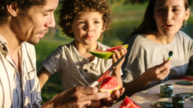 Family at picnic eating watermelon.