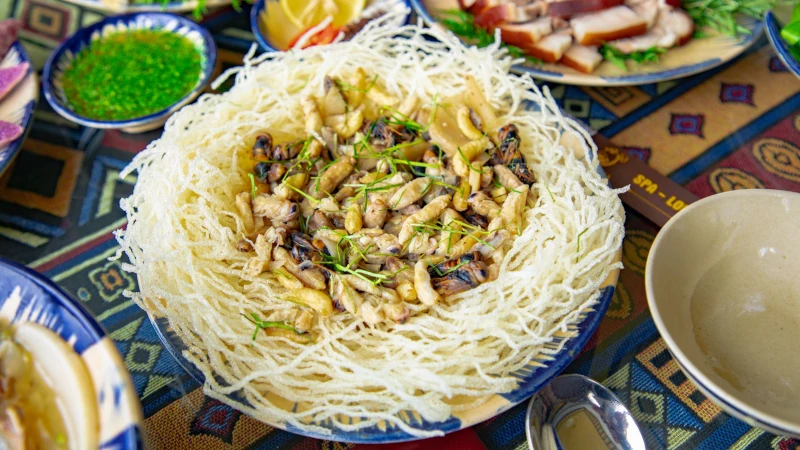 A unique culinary presentation featuring insects in a crispy noodle nest served with fresh herbs.