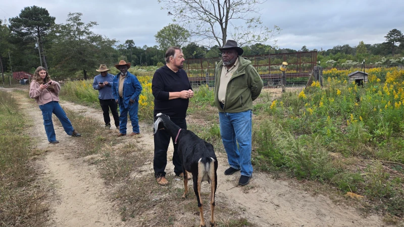 Two men discussing farm matters with a goat.