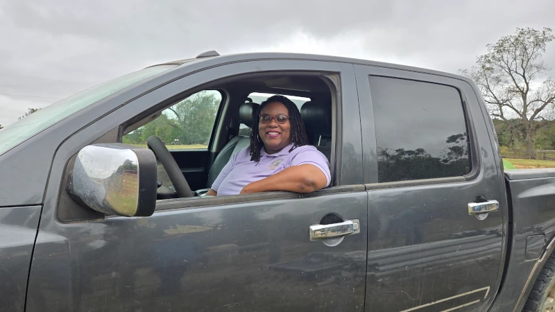 Woman in drivers seat of her truck smiling, posing for a picture.