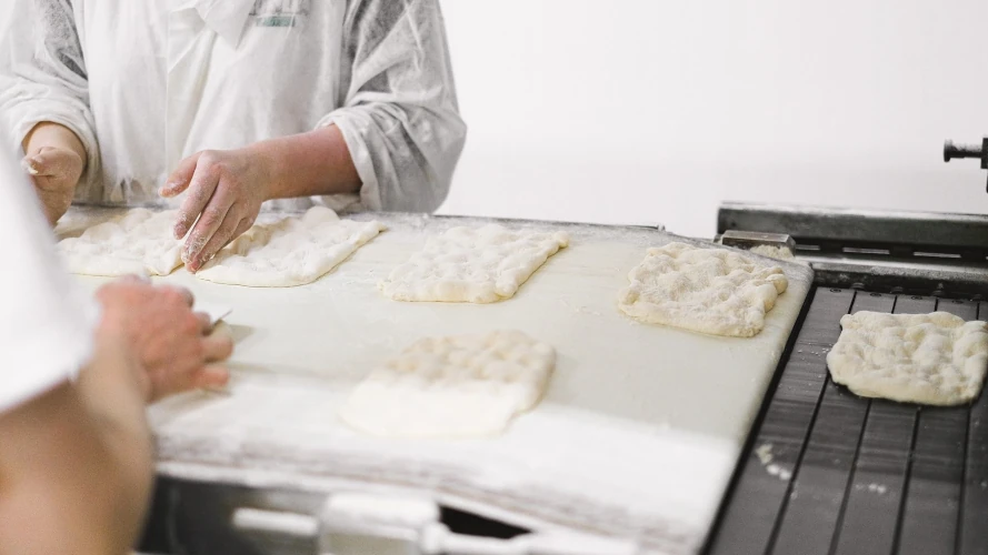 Close-up of bakers shaping dough on a worktable, preparing fresh bread in a bakery