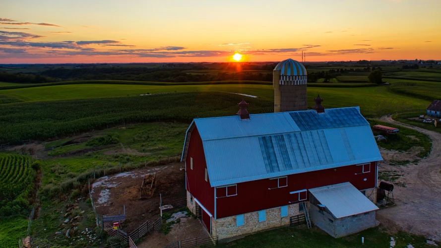 Aerial view of a red barn at sunset surrounded by lush fields in Minnesota's countryside.
