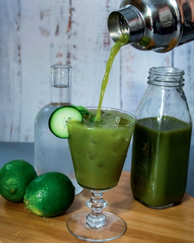 Matcha Mint Garden and Tonic drink being poured from the shaker into a glass with a cucumber garnish.