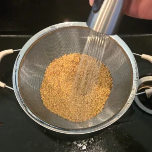 Lentils being rinsed in a colander.