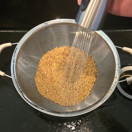 Lentils being rinsed in a colander.