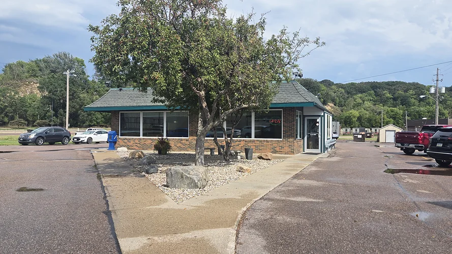 Exterior of Johnnie Mars restaurant, a brick building with a green roof and a tree out front.