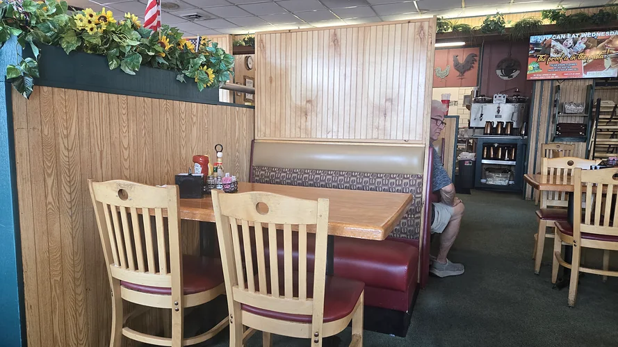 A wooden table and booth at Johnnie Mars beneath a planter of sunflowers.