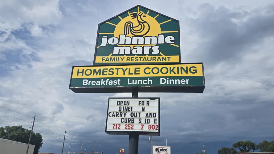 Johnnie Mars Family Restaurant roadside sign reading Homestyle Cooking, Breakfast, Lunch, Dinner, under a cloudy sky.